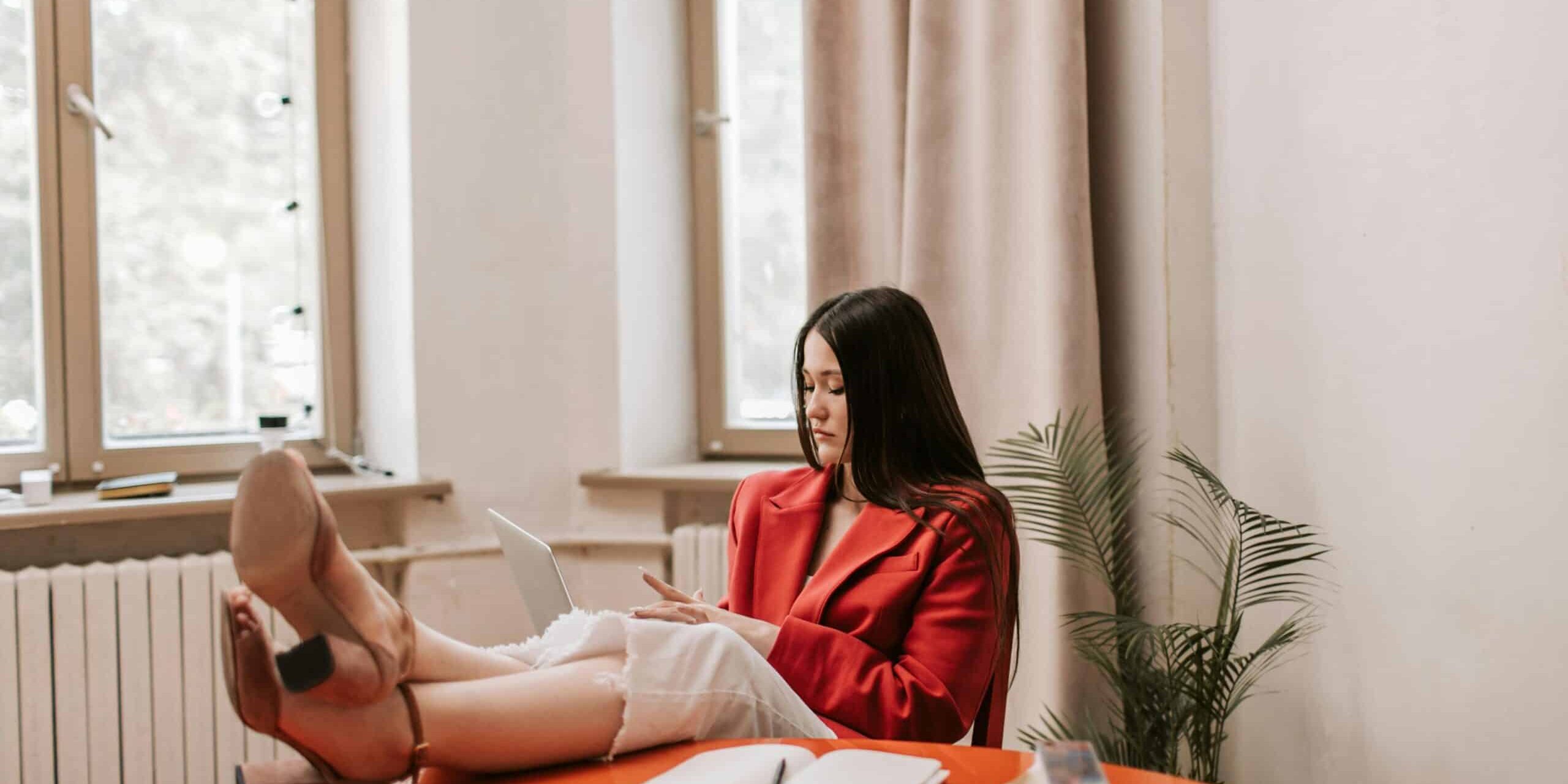 A Woman in Red Blazer Using a Laptop with energy efficient windows at the side